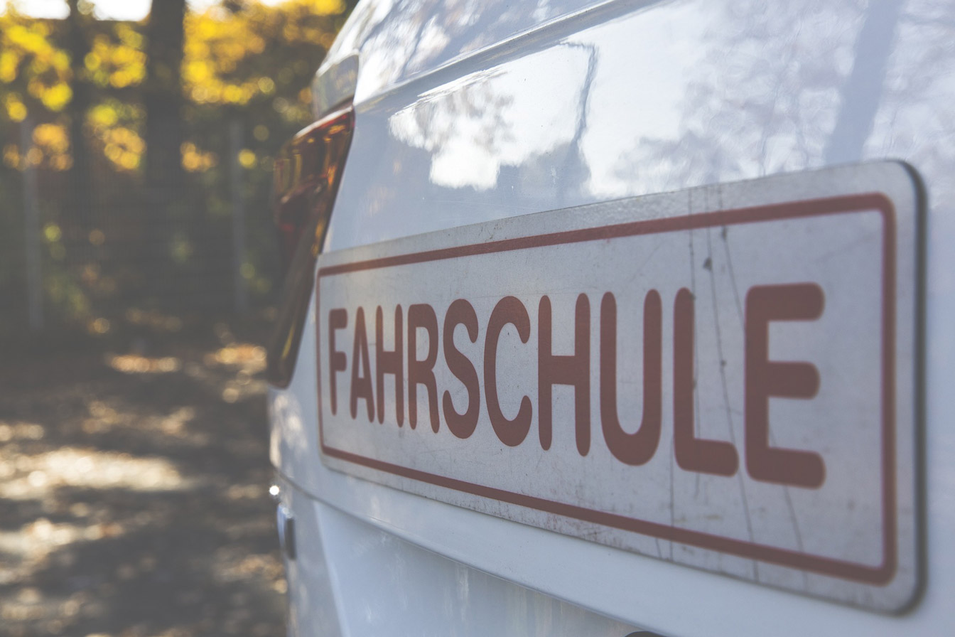 Fahrschulwagen mit dem Schriftzug 'Fahrschule' auf der Fahrzeugseite.